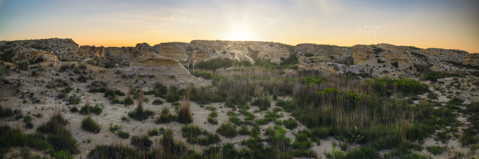 A gravel road stretching towards a warm prairie sunset panorama